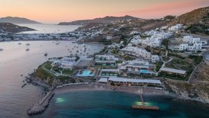 foto blick von einem helikopter rundflug aus von oben auf das grosse resort direkt am meer auf einem kleinen berg mit vielen weissen häusern und dem hafen im hintergrund des luxuriösen hochklassigen exklusiven designer hotel santa marina auf mykonos in gr